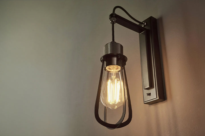 Industrial style wall sconce with a cage frame and exposed filament bulb