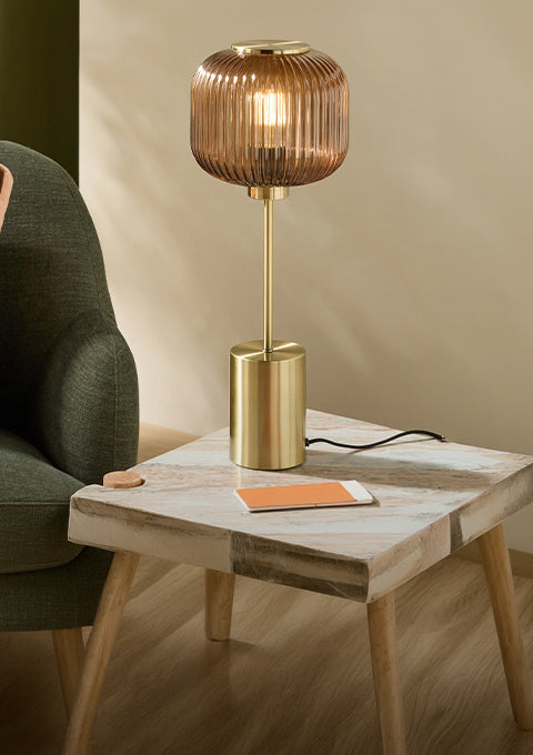 Table lamp with ribbed amber glass shade and brass base on a wooden side table