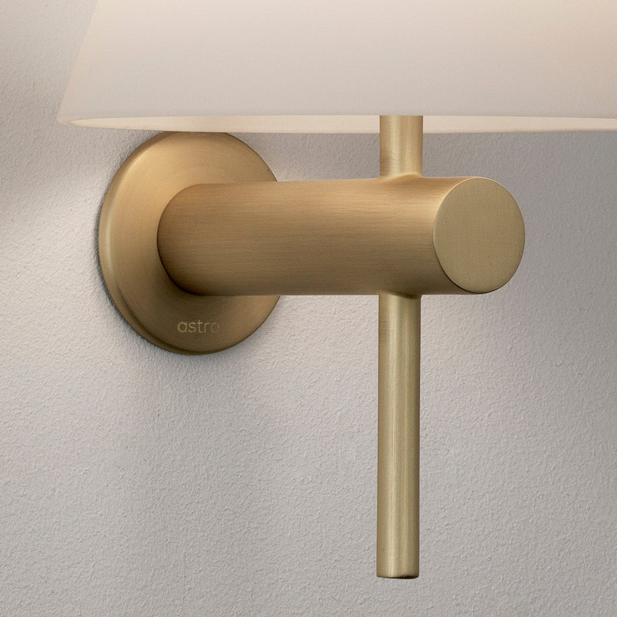 A close-up of a brass wall light with a white fabric shade
