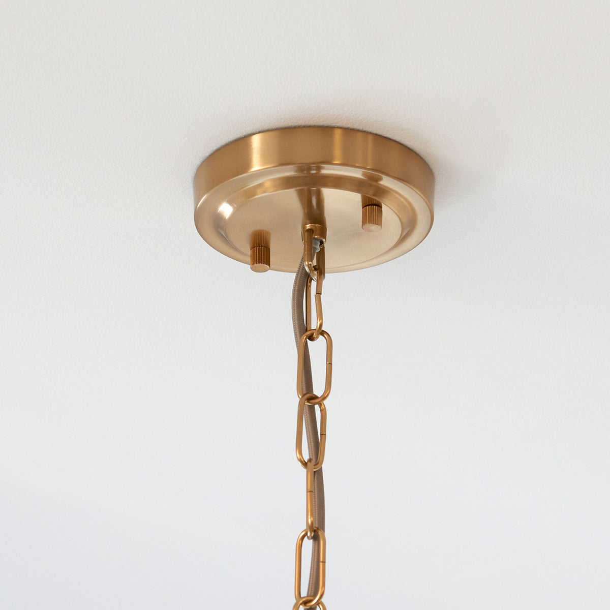 Close-up of a gold ceiling plate and chain for a pendant light fixture.