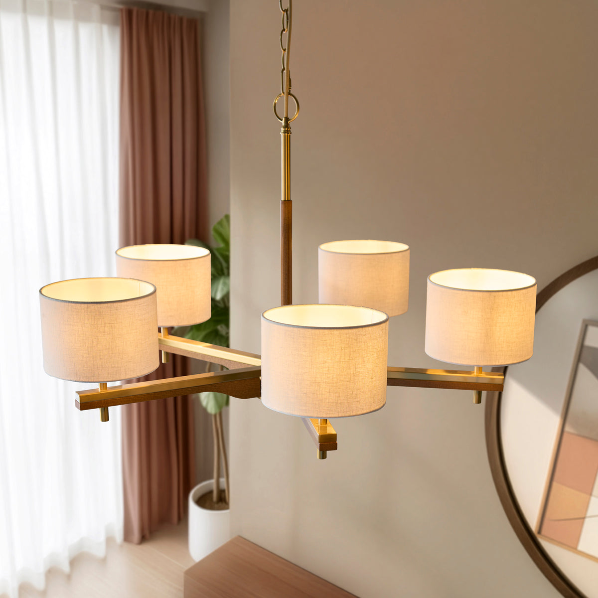 Modern chandelier with five fabric shades and a brass and wood frame, illuminating a room with soft light.