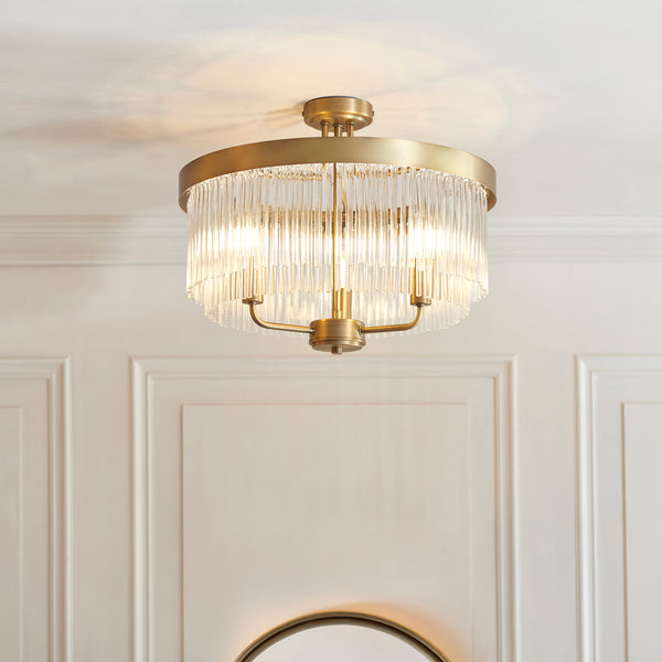 A close-up of a gold and glass chandelier, with light shining through the glass rods.