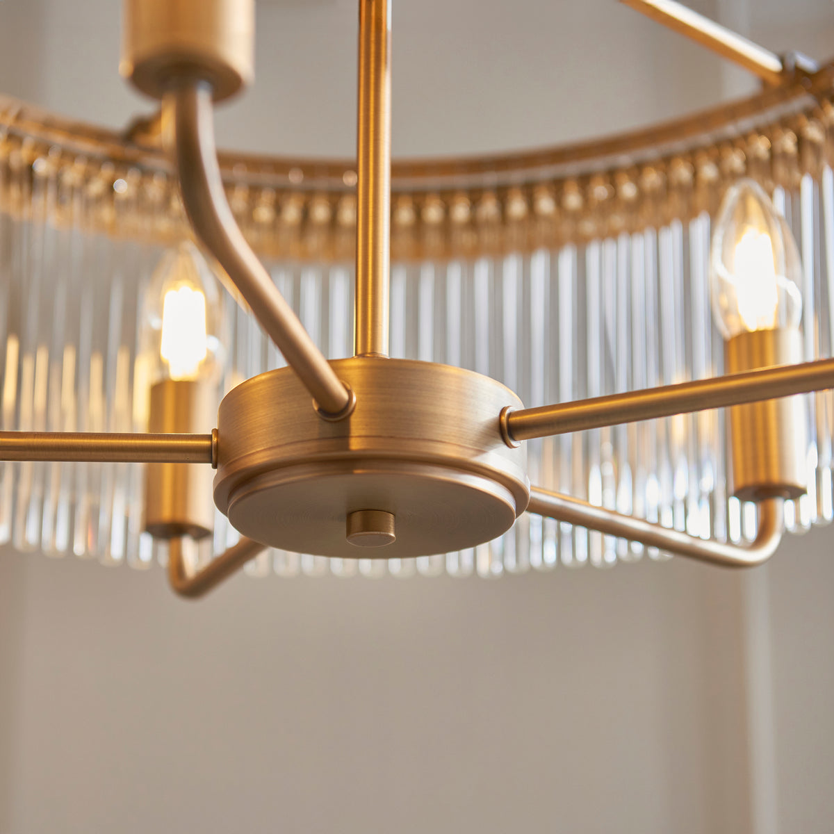 Close-up of a brass chandelier with exposed bulbs and glass rods.