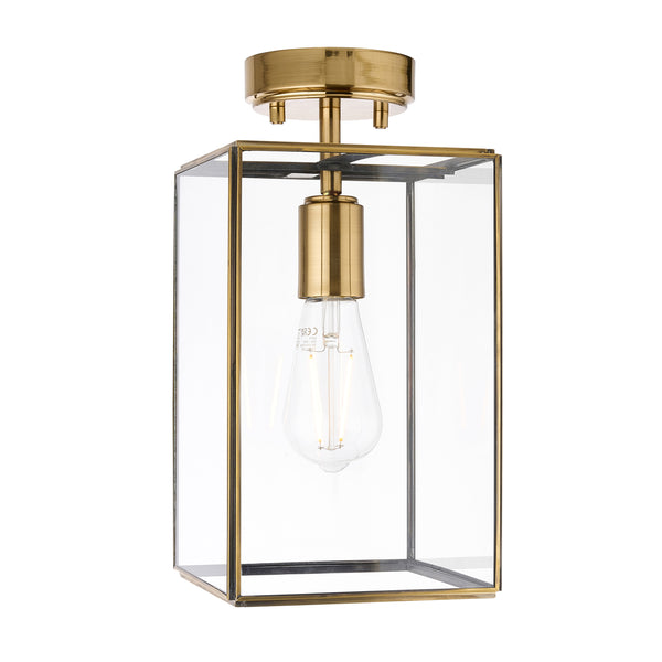 A brass and glass semi-flush mount ceiling light with an exposed Edison bulb.