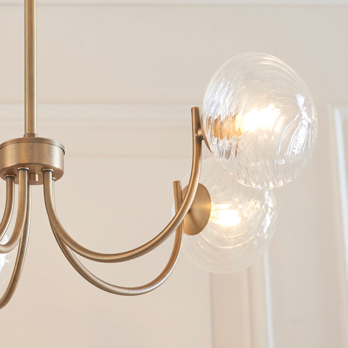 Close-up of a brass chandelier with two illuminated, textured glass globes.