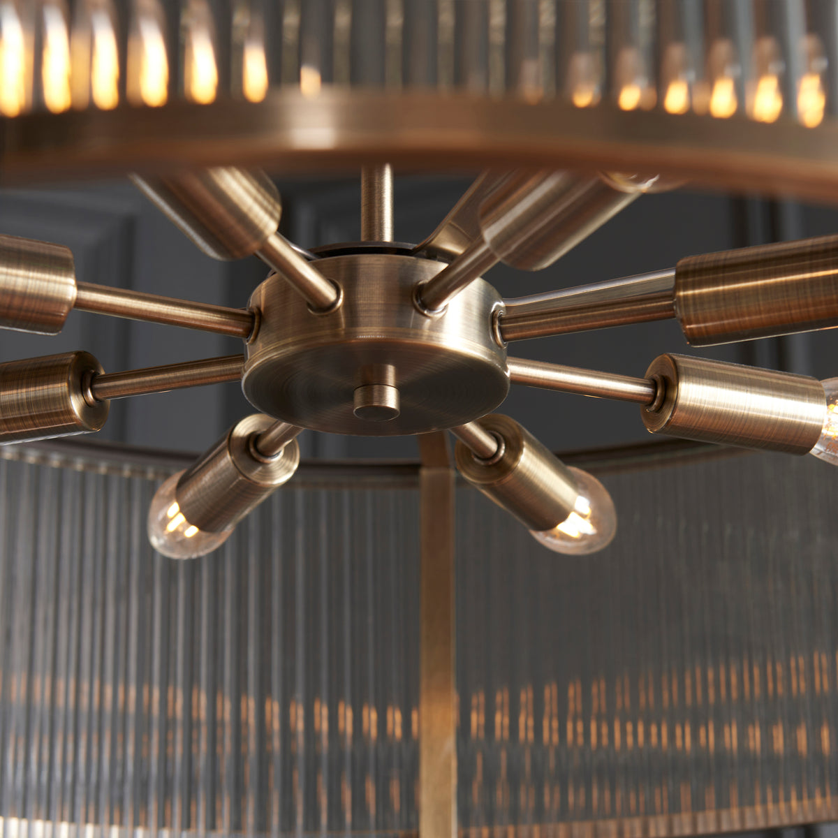 Close-up of a brass chandelier with exposed bulbs and a fluted glass shade.