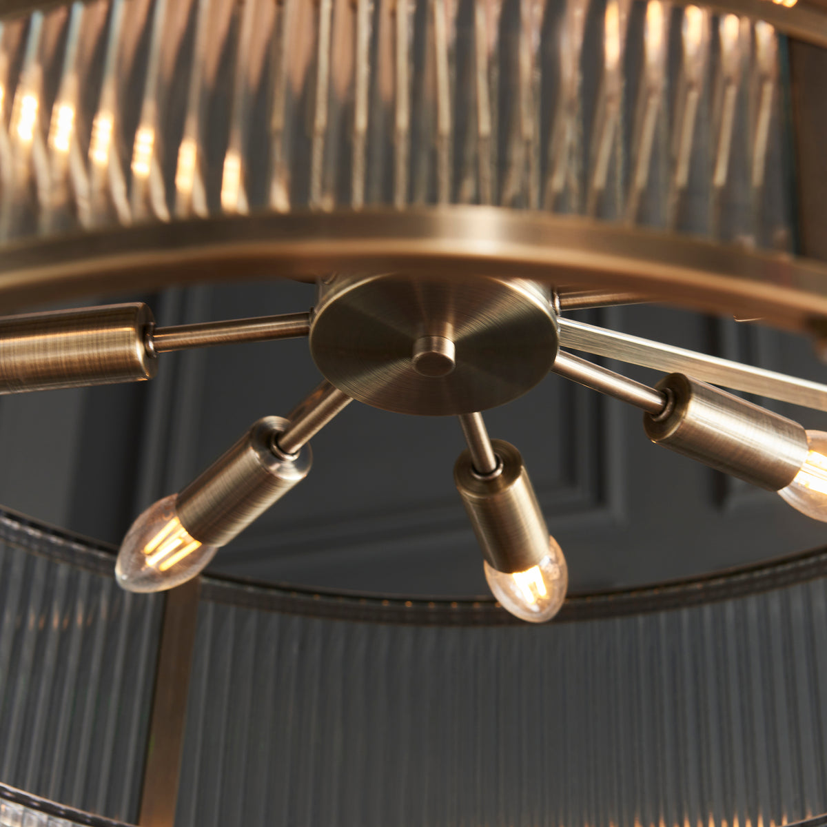Close-up of a brass chandelier with exposed bulbs and a fluted glass shade.