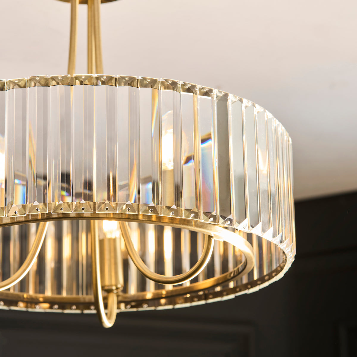 Close-up of a brass chandelier with rectangular crystal panels, glowing with warm light.