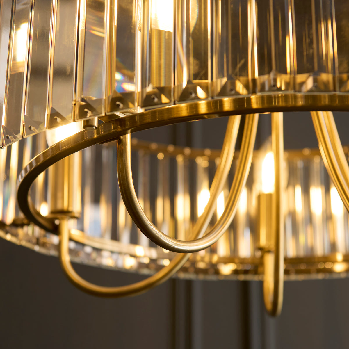 Close-up of a gold chandelier with rectangular crystal panels and glowing bulbs.