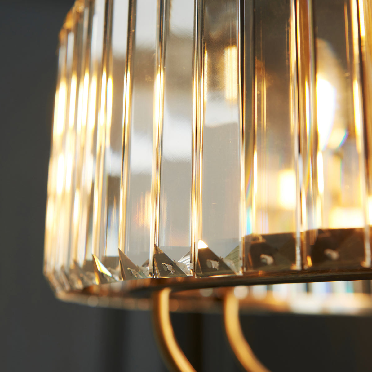 Close-up of a fluted glass lampshade with warm light glowing through, showing intricate details and reflections.