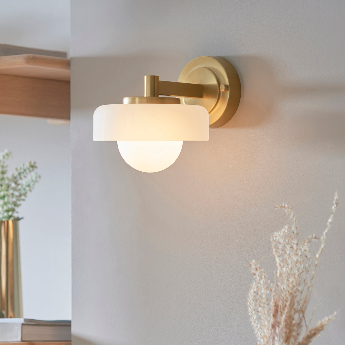Endon Lighting Boss wall light in brushed aged brass with matt opal sphere glass shade mounted on a wall