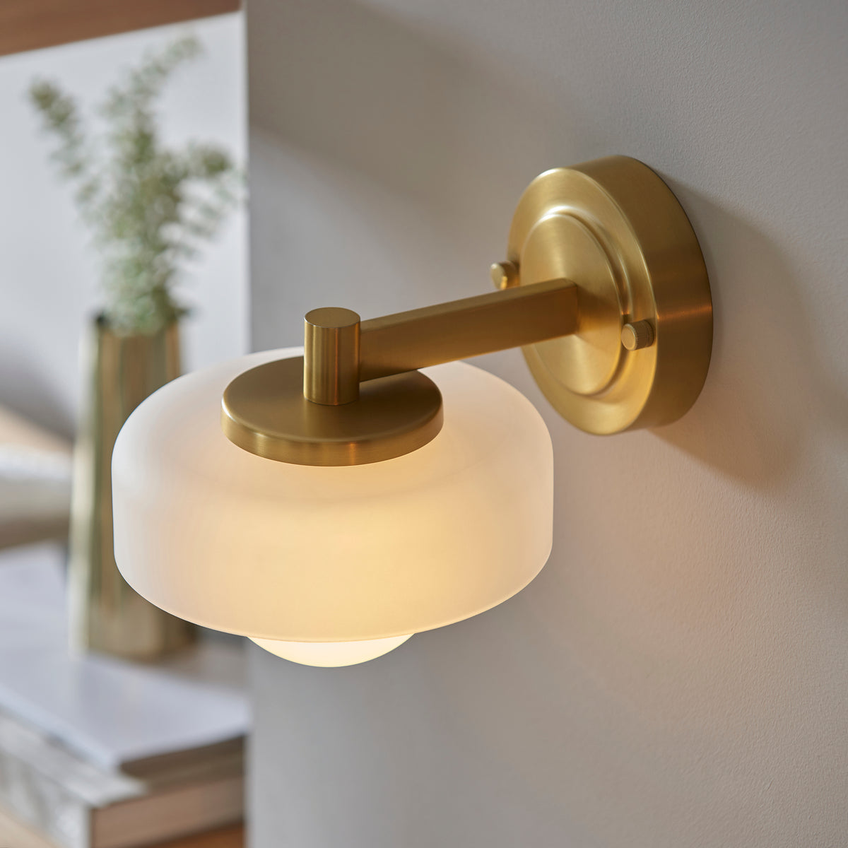 Endon Lighting Boss wall light in brushed aged brass with a matt opal sphere glass shade mounted on a wall