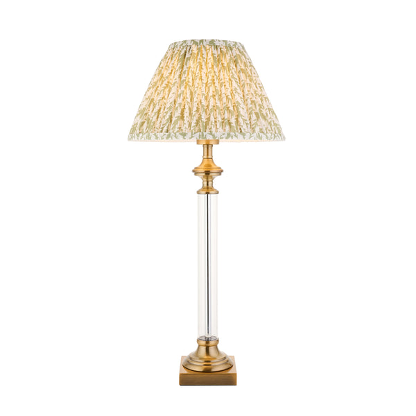 Table lamp with a pleated, patterned shade in green and cream, a clear glass column, and a brass base.