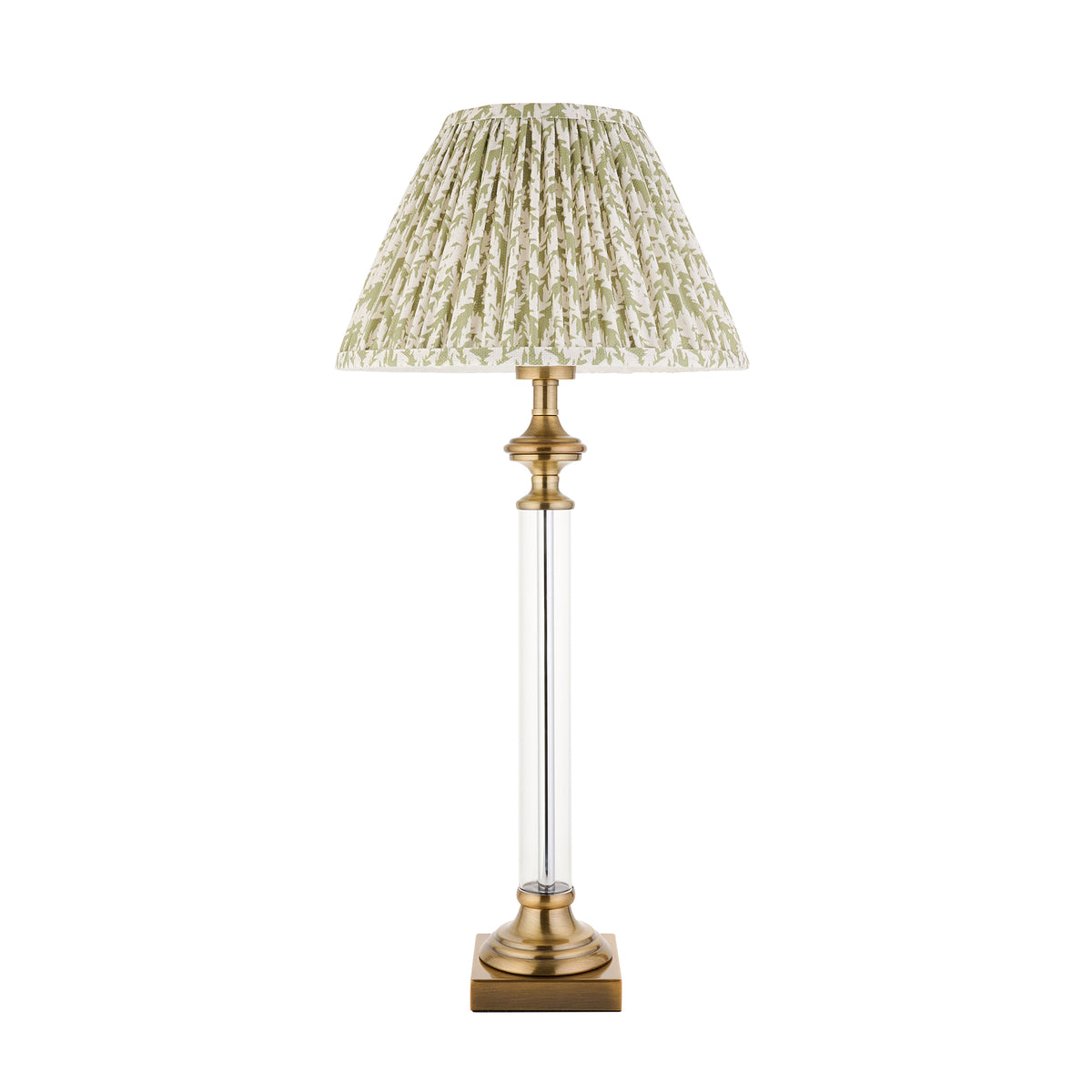 A table lamp with a clear glass column, brass base, and a pleated green and white patterned shade. 