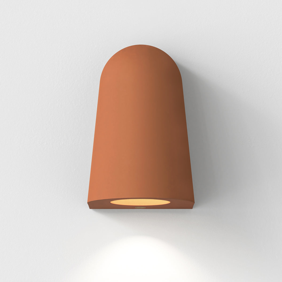 Terracotta wall light with an arched top and a circular light source at the bottom