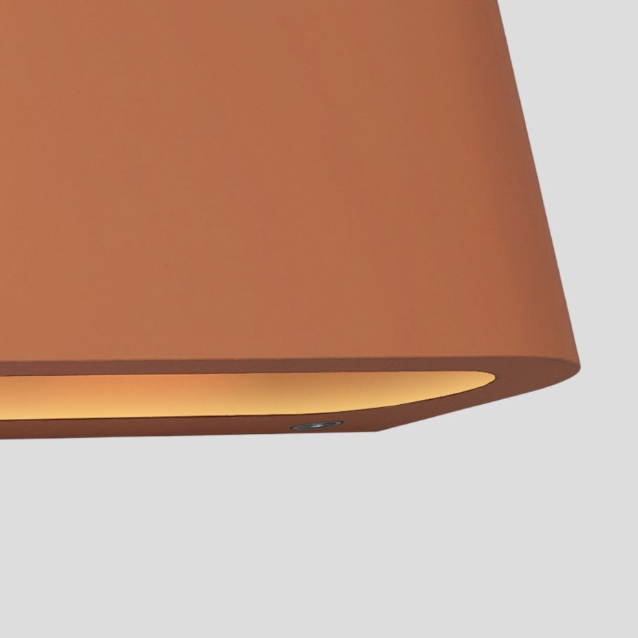 Close up of a terracotta colored light fixture with a warm glow