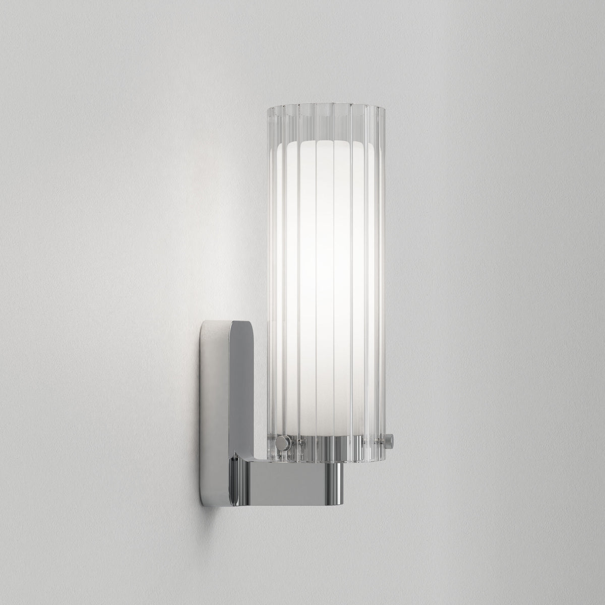 Polished chrome wall sconce with a ribbed glass shade and an illuminated white diffuser
