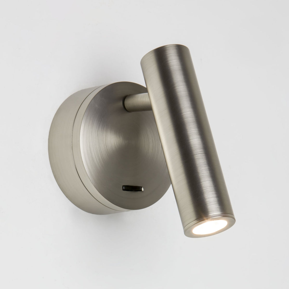 Brushed nickel wall light with a cylindrical adjustable head and a round base