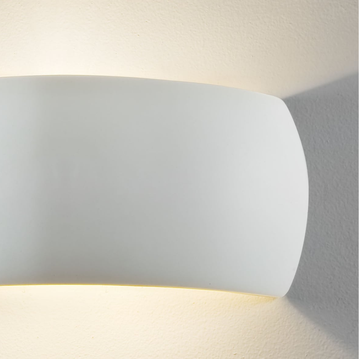 White curved wall light illuminating a textured white wall