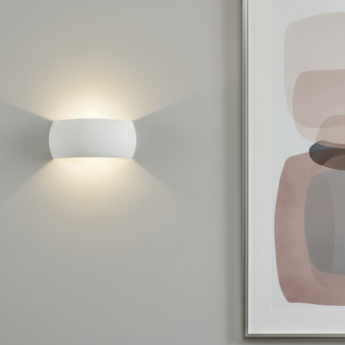 White wall light with light shining up and down on a grey wall next to a framed abstract print