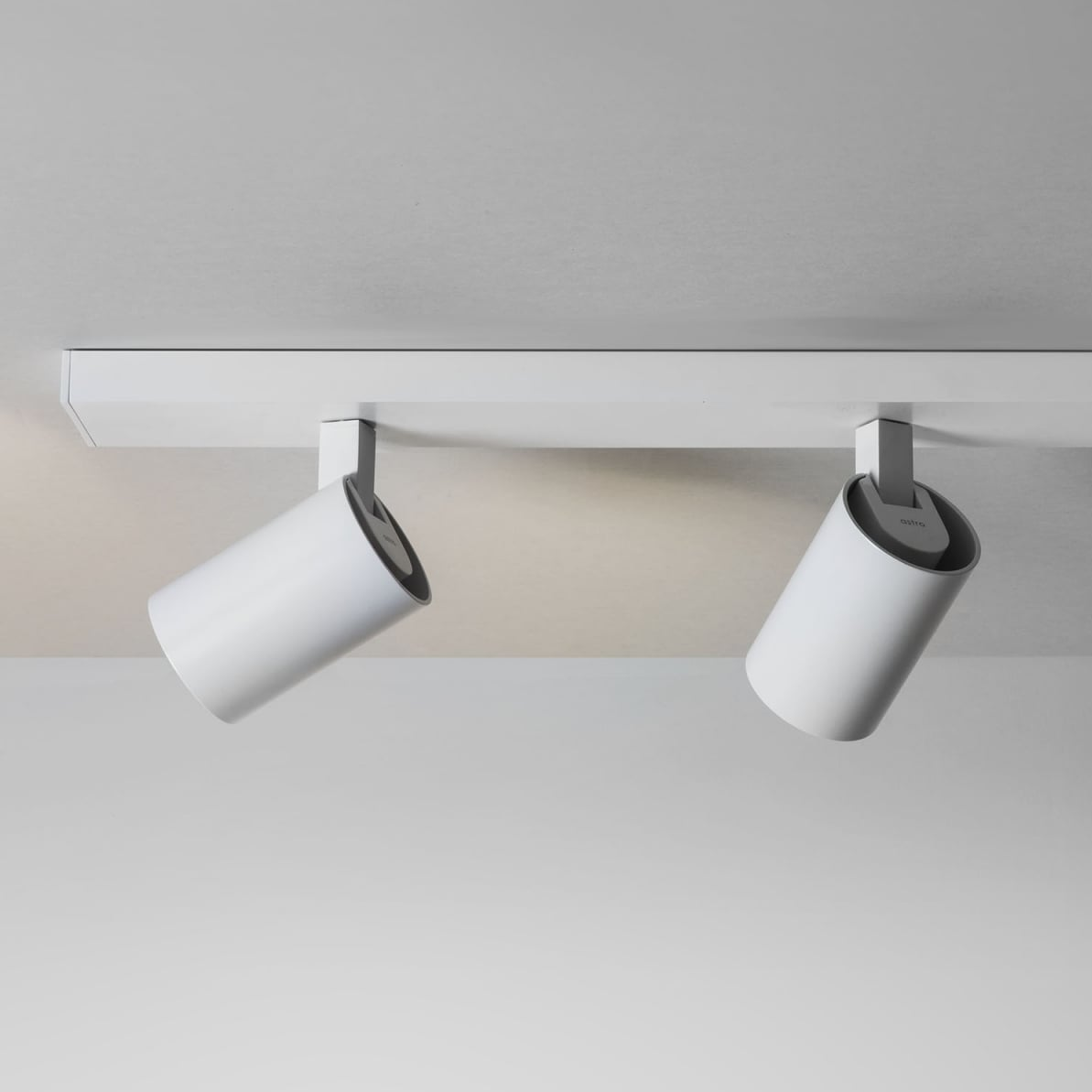 Two white cylindrical track lights mounted on a white ceiling track