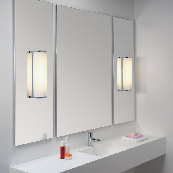 Bathroom vanity with three mirrors, two wall sconces, a sink, and toiletries