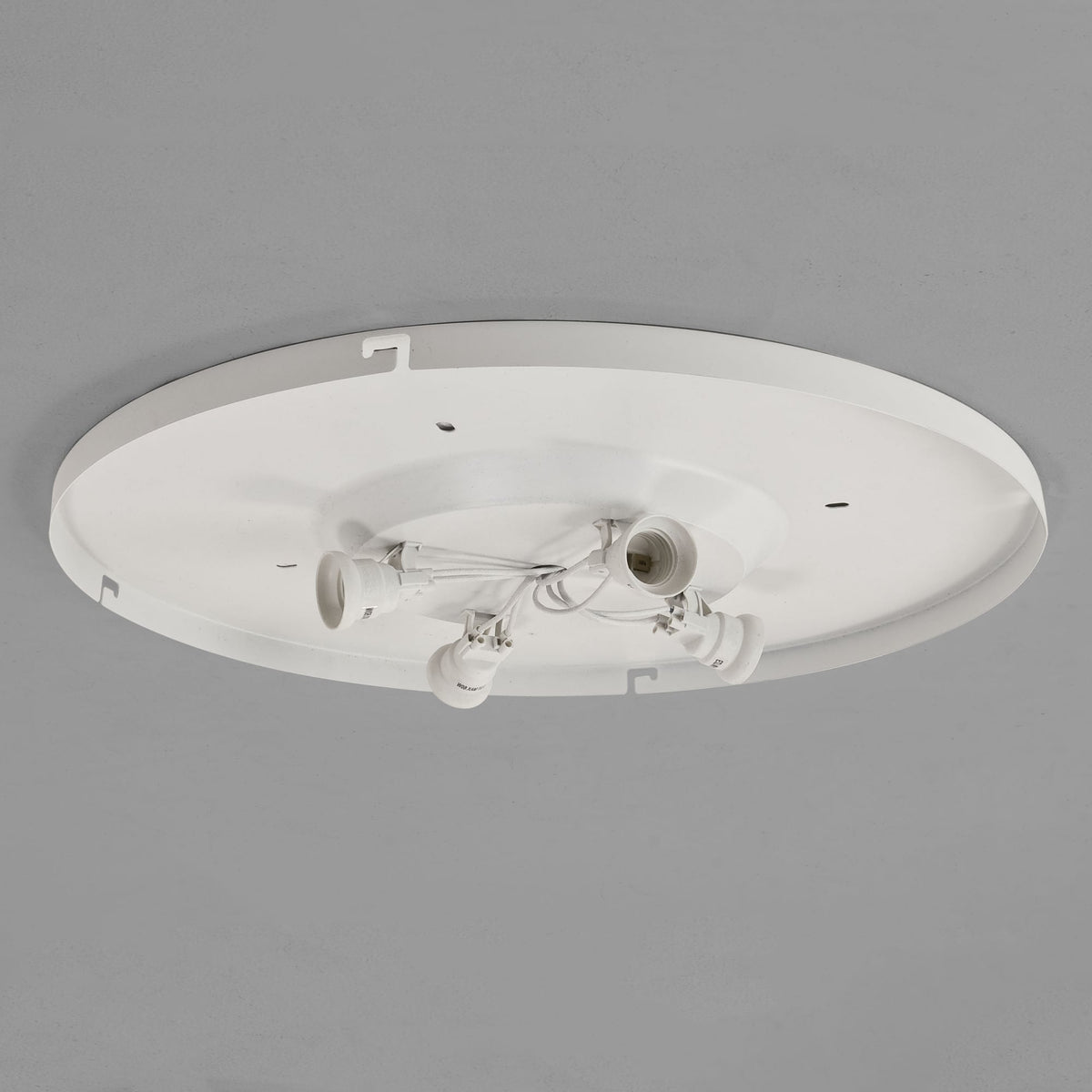White circular ceiling light fixture base with four exposed bulb sockets and wiring