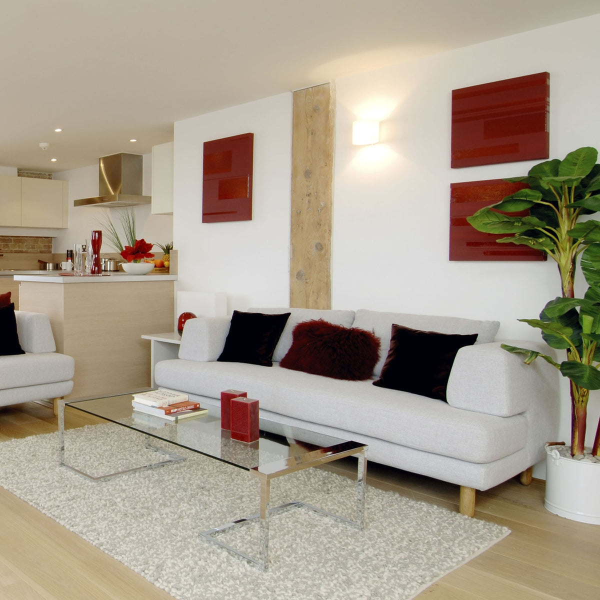 Living room with a light grey sofa, glass coffee table, and red wall art