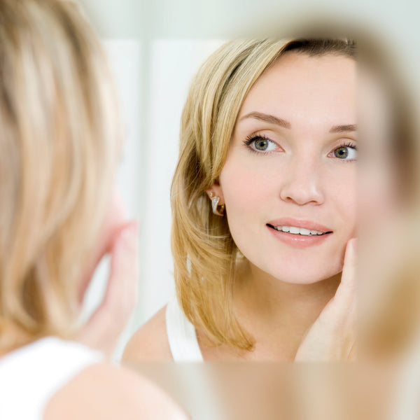 Woman looking at her reflection in a mirror, touching her cheek