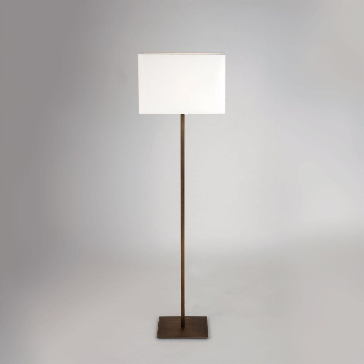 A tall, slender floor lamp with a rectangular white shade and a dark bronze finish.