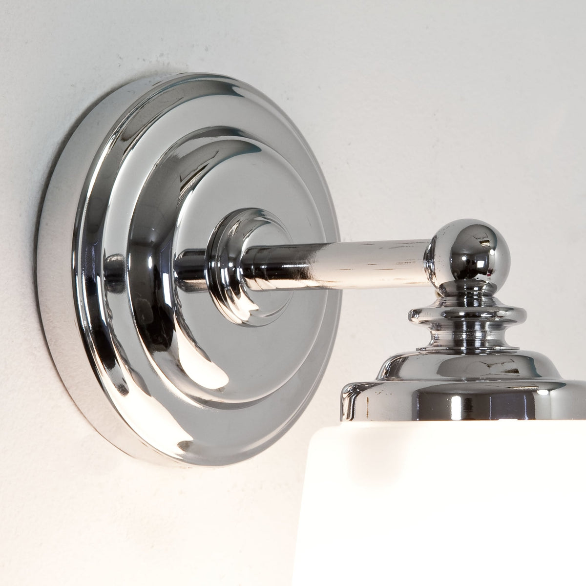 Chrome wall sconce with a white glass shade