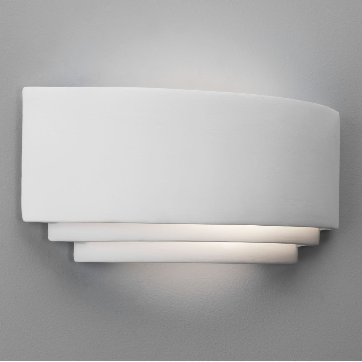 White rectangular wall light with a curved top and layered bottom, casting light upwards and downwards.