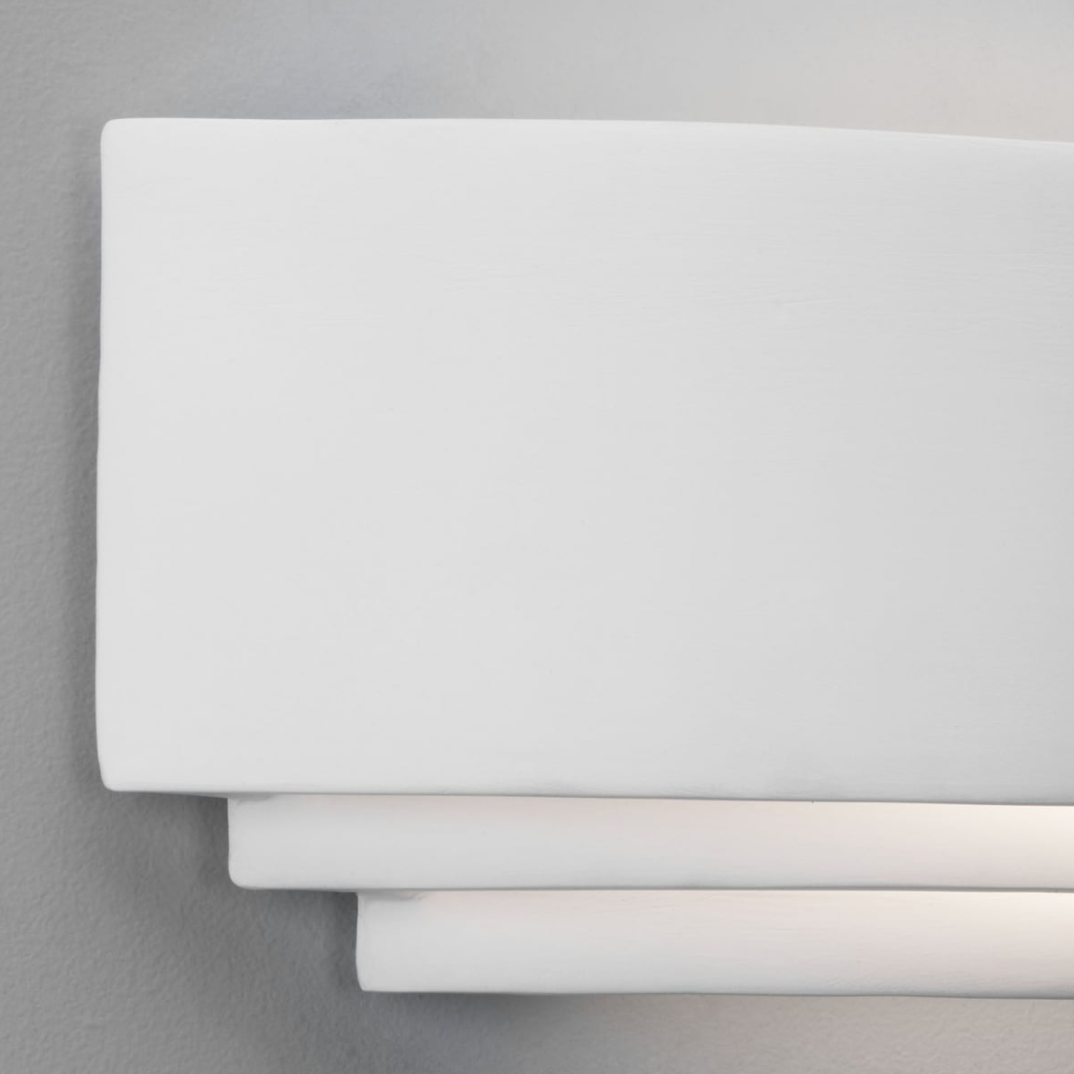 White rectangular wall sconce with light shining from between the layers