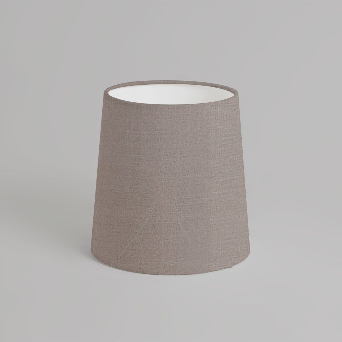 Tapered drum lampshade in a light brown fabric with a white interior