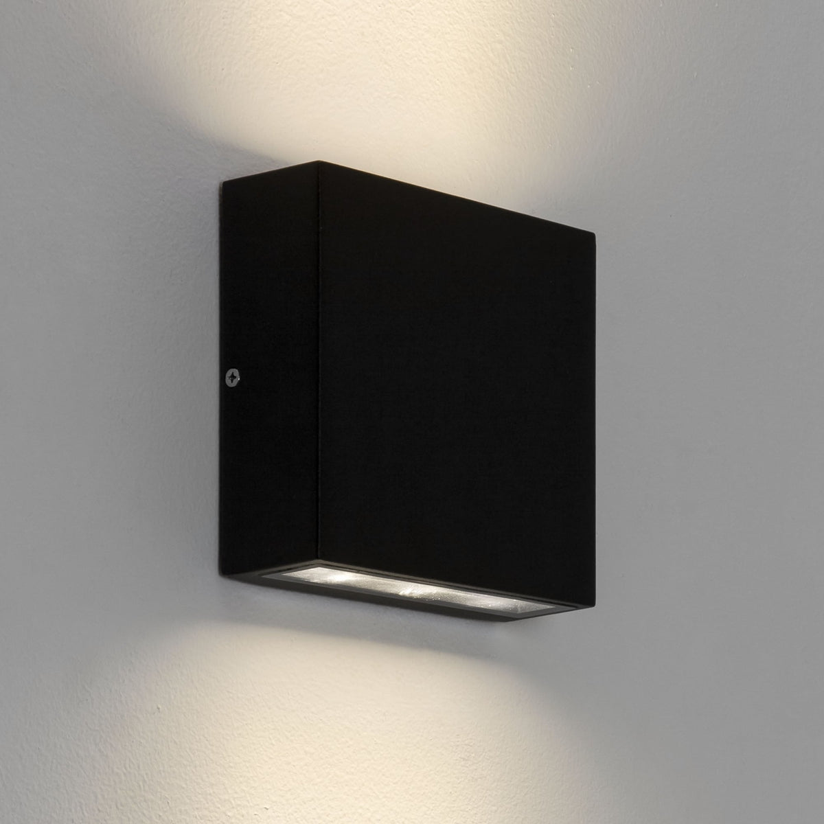 Black square wall light with warm light shining up and down on a white wall