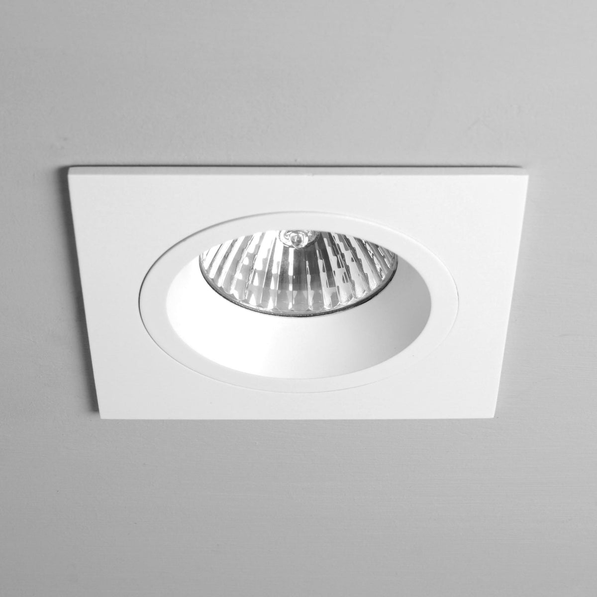 White square recessed ceiling light with a round bulb