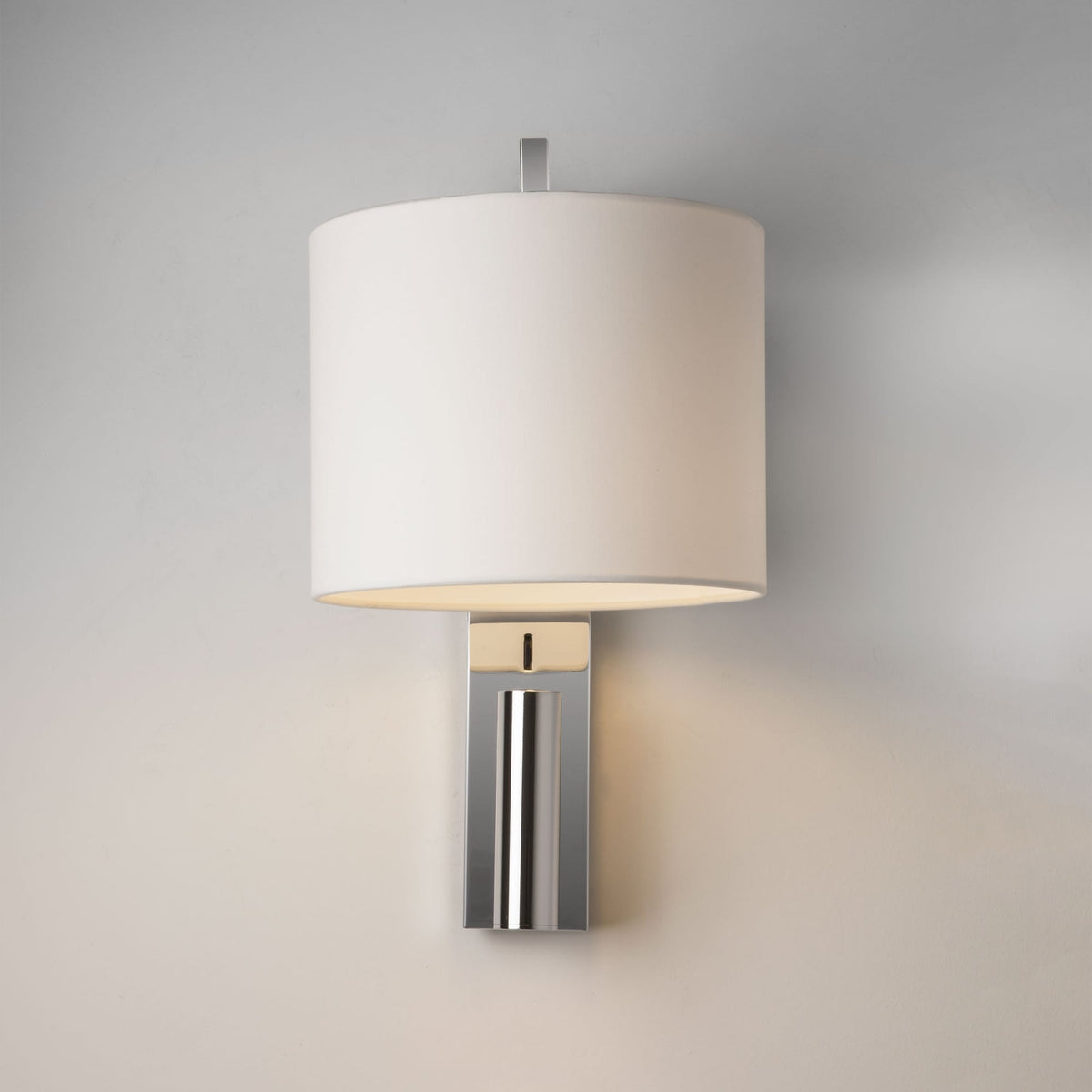 Wall-mounted light fixture with a white cylindrical shade and a polished chrome base