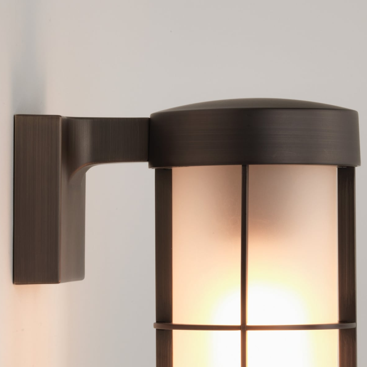 Close up of a bronze outdoor wall light with a frosted glass shade
