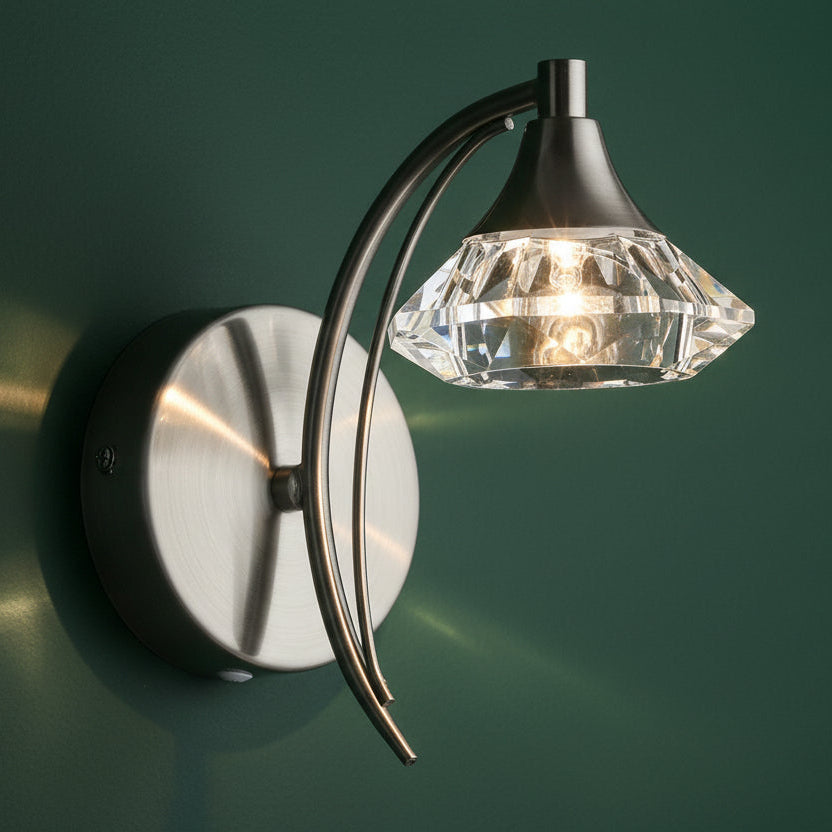 Brushed steel wall light with a curved arm holding a faceted crystal shade.