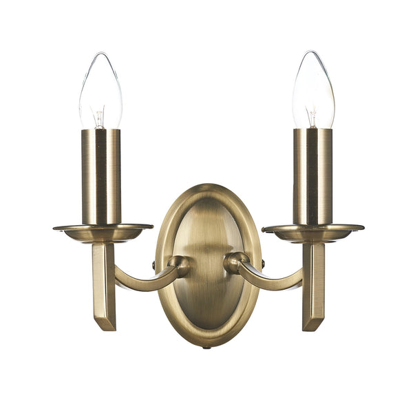 A vintage brass wall light with two candle-style bulbs.