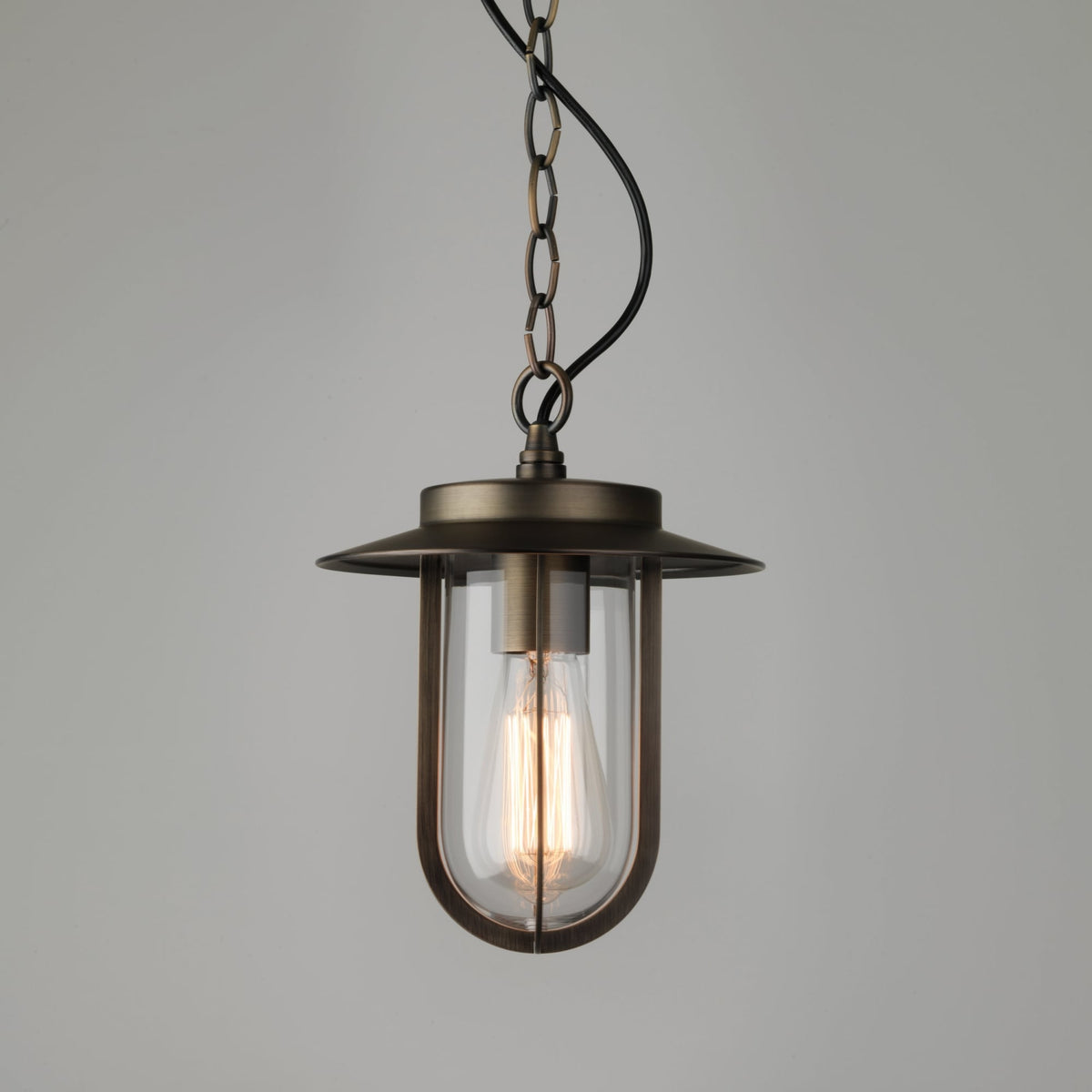 Bronze pendant light with a clear glass shade and an exposed filament bulb