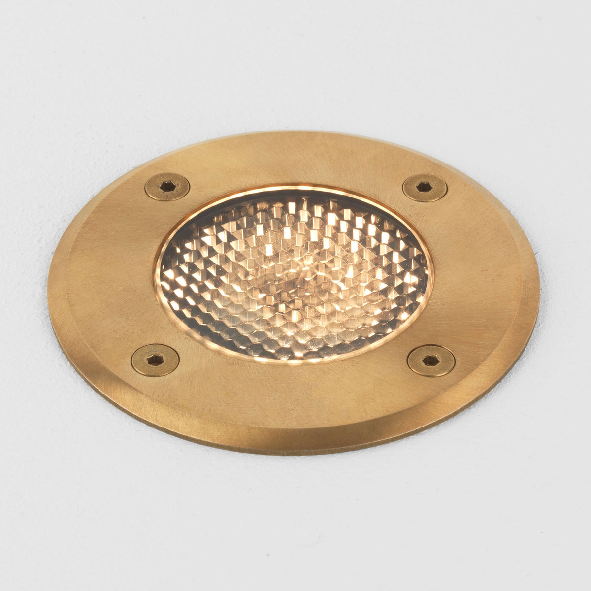 Round brass ground light with a textured glass lens and four visible screw heads