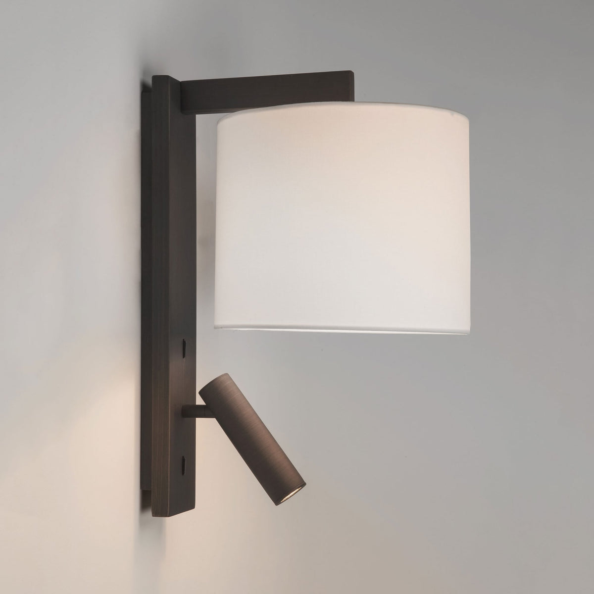 Wall mounted lamp with a white cylindrical shade and an adjustable reading light below