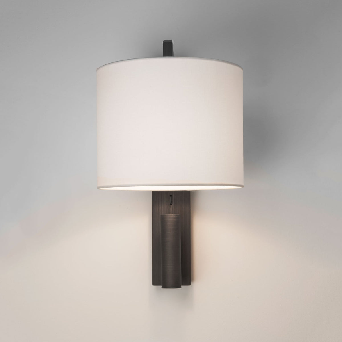 Wall-mounted light fixture with a white cylindrical shade and a dark bronze base
