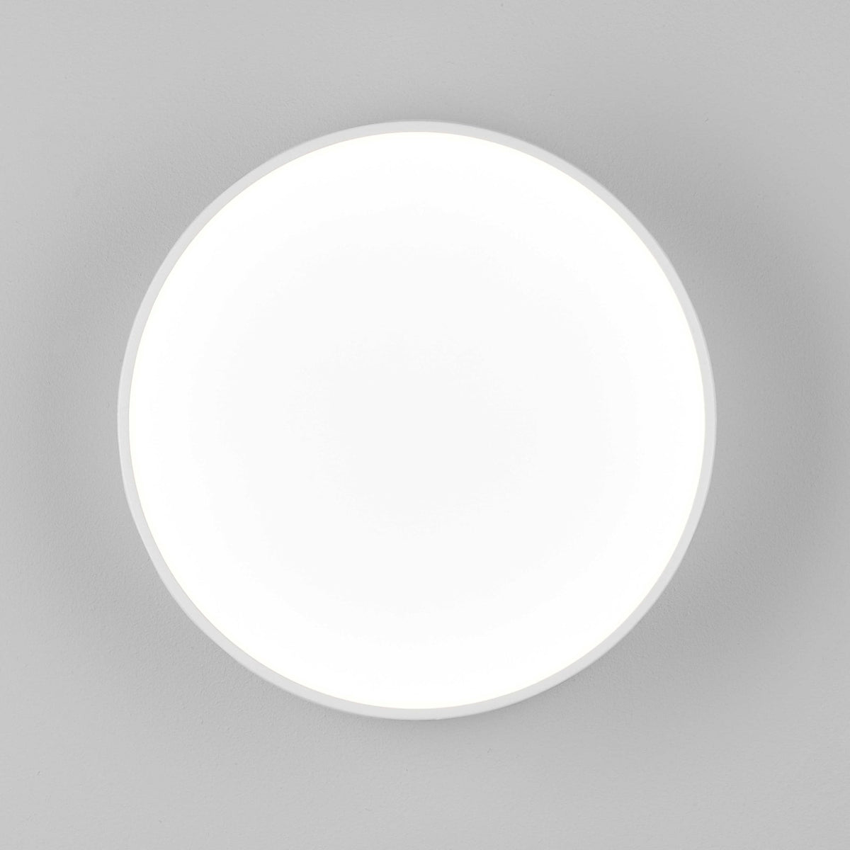 A round ceiling light provides even, diffused illumination against a grey background.