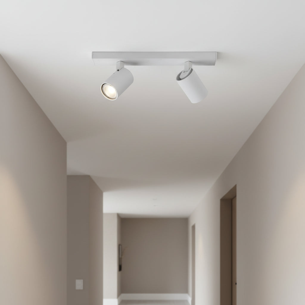 Two white ceiling spotlights on a track in a hallway, one light is on