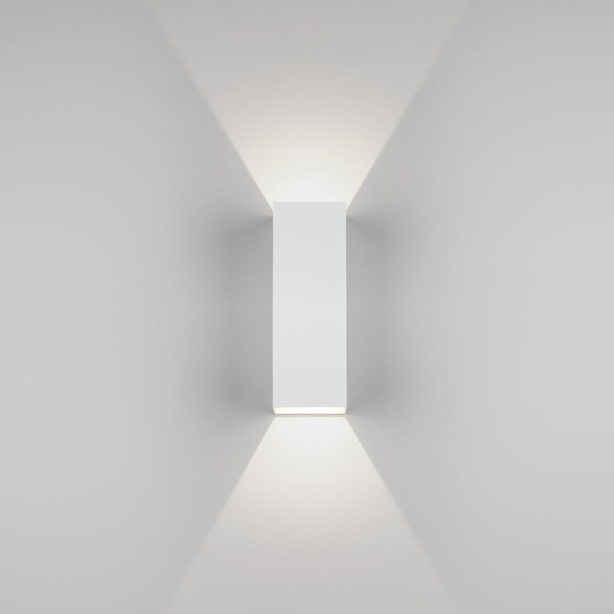 White rectangular wall light fixture with light shining upwards and downwards on a white wall