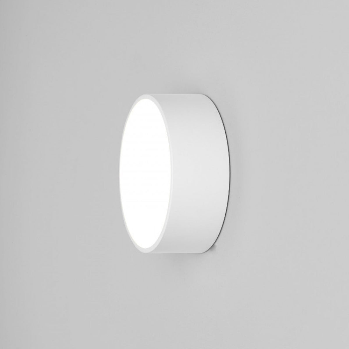 White round wall light with a glowing front surface, mounted on a light grey wall