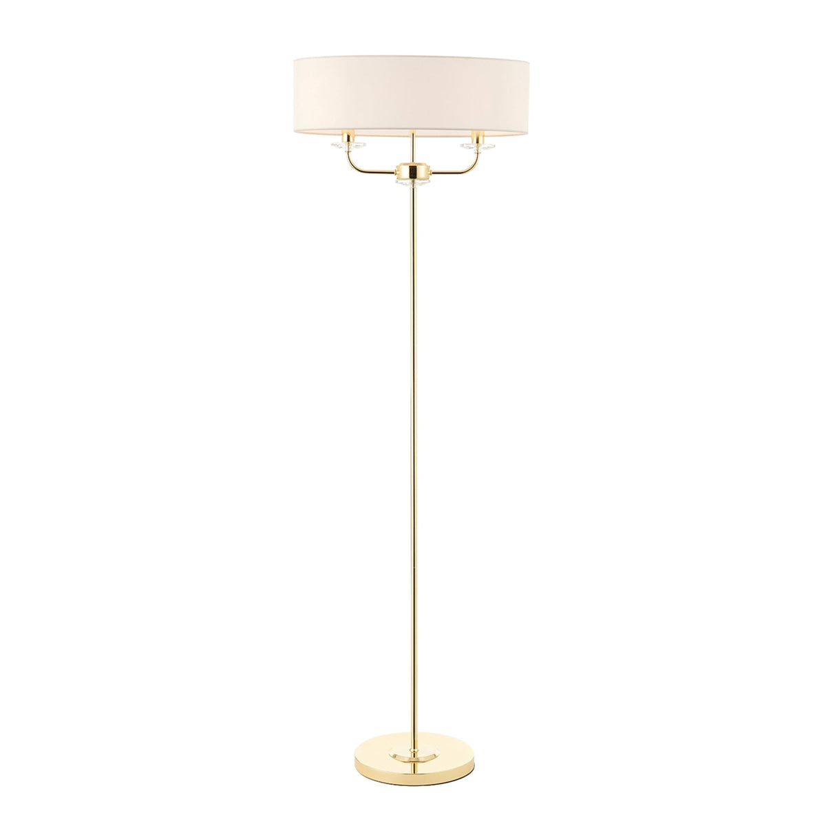 A tall, slender floor lamp with a brass finish and a cream-colored drum shade.