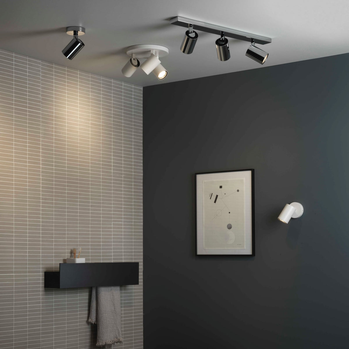 A modern bathroom with grey tiled walls and a dark grey painted wall, featuring various ceiling and wall spotlights